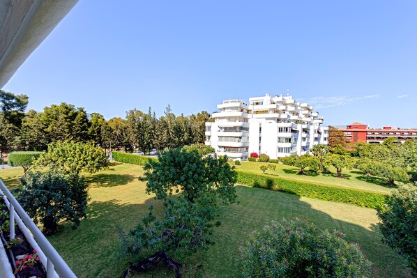 Un immeuble résidentiel à plusieurs étages, doté de balcons, entouré de pelouses et d’arbres bien entretenus.