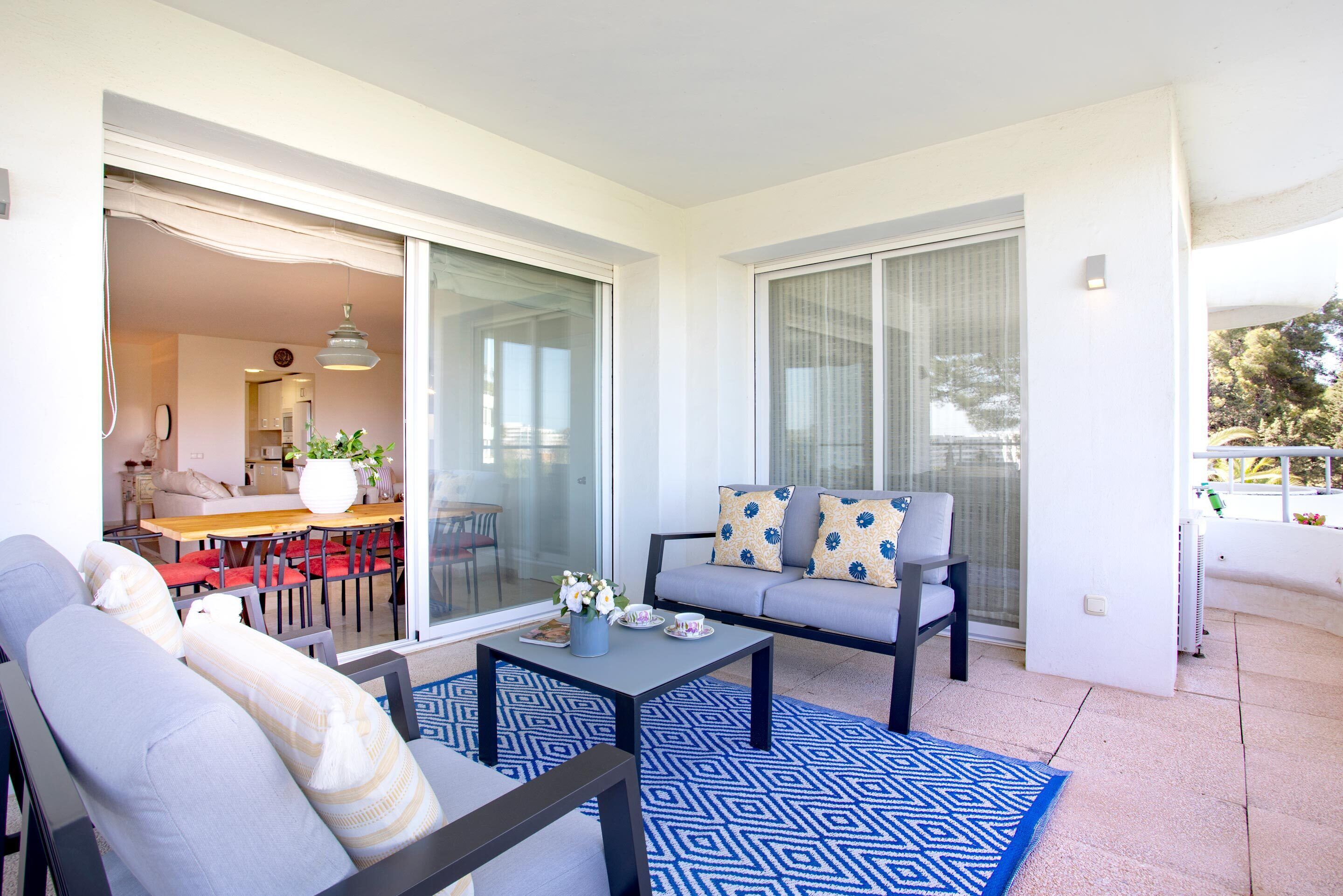 A modern living room with a sofa, a coffee table, and a dining area with chairs and a table.