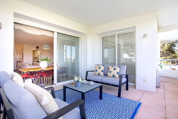 A modern living room with a sofa, a coffee table, and a dining area with chairs and a table. - Genteel Home Los Flamencos Terrace (Marbella)