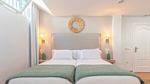 Un lit double avec deux oreillers, un grand miroir rond au-dessus, et deux tables de chevet avec des lampes et des vases.