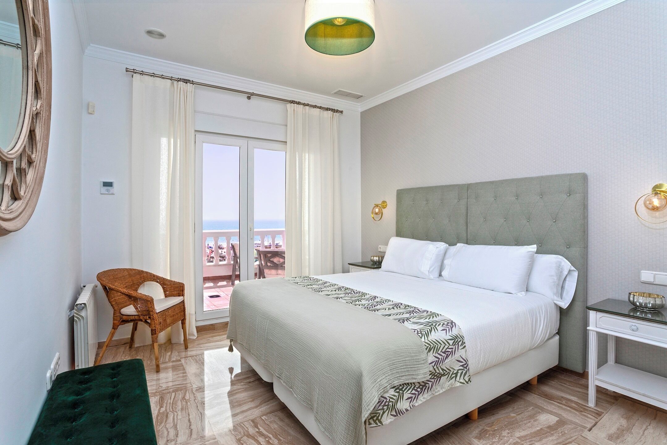 Habitación de hotel con una cama grande, una silla, una mesita y vistas al exterior.