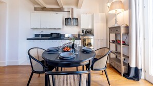 A modern kitchen with white cabinets, a round dining table with black chairs, and a wooden floor. - Genteel Home Scarlatti (Florence)