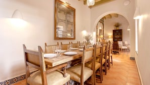 A dining area with a long wooden table set for six, surrounded by wooden chairs with cushioned seats. - Genteel Home Pimienta (Seville)