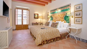 A bedroom with a bed, a television, a door, and a wall with framed pictures. - Genteel Home Pimienta (Seville)