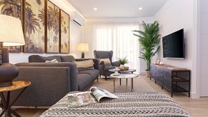 Een moderne woonkamer met een bank, fauteuil, salontafel en een flatscreen televisie.