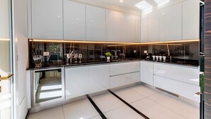 A modern kitchen with white cabinets, black countertops, and a central island with a sink. - Genteel Home Prato (Prato)