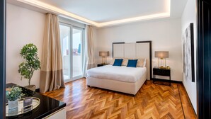 A modern hotel room with a large bed, two bedside tables, a nightstand, a potted plant, and a view of the city through the window. - Genteel Home Prato (Prato)