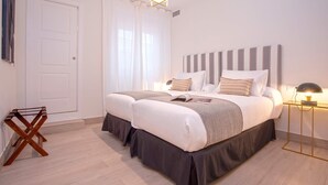 A double bed with a striped headboard, a bedside table with a lamp, and a wooden chair. - Genteel Home Teatro Gongora (Córdoba)