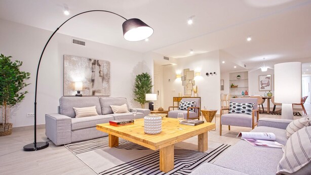 A modern living room with a grey sofa, a wooden coffee table, and a floor lamp. - Genteel Home Teatro Gongora (Córdoba)