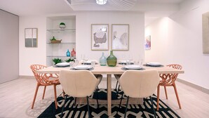 A modern dining area with a wooden table, orange chairs, and a black and white patterned rug. - Genteel Home Teatro Gongora (Córdoba)