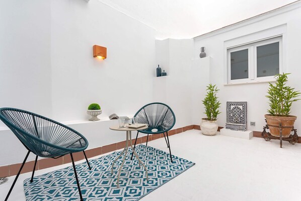 Un pequeño patio con dos sillas, una mesa y plantas en macetas.