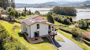 Una casa moderna con terraza, vistas a un lago y follaje circundante.