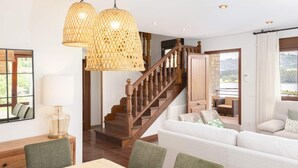 Un espacio habitable amplio con una escalera de madera, una mesa de comedor y un ventanal con vistas al exterior.