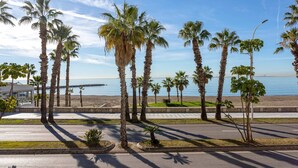 A coastal road lined with palm trees and a beach in the background. - Genteel Home Paseo Marítimo (Málaga)