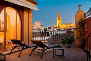 A terrace with two lounge chairs and a table, overlooking a cityscape with a prominent tower. - Genteel Home San Isidoro Terrace (Seville)