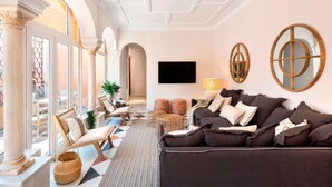 A spacious living room with a large sofa, a television, and a view of the outdoors through large windows. - Genteel Home San Isidoro Terrace (Seville)