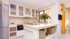 Una cucina moderna con mobili bianchi, forno integrato e isola centrale con lavello.