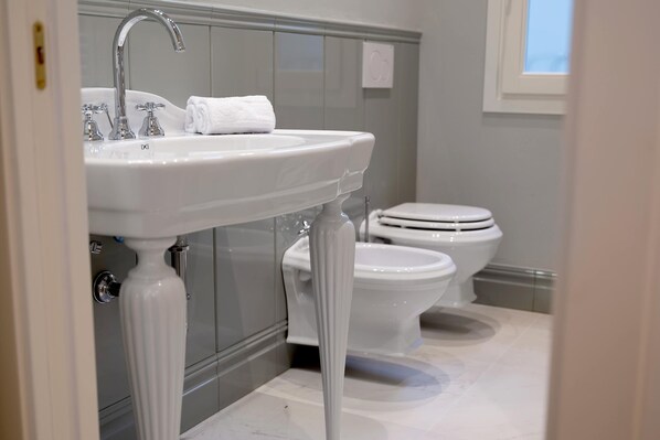 A bathroom with a white sink, two toilets, and a window.