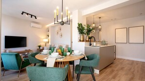 Un salon moderne comprenant un coin repas, un téléviseur à écran plat et une cuisine avec un bar.