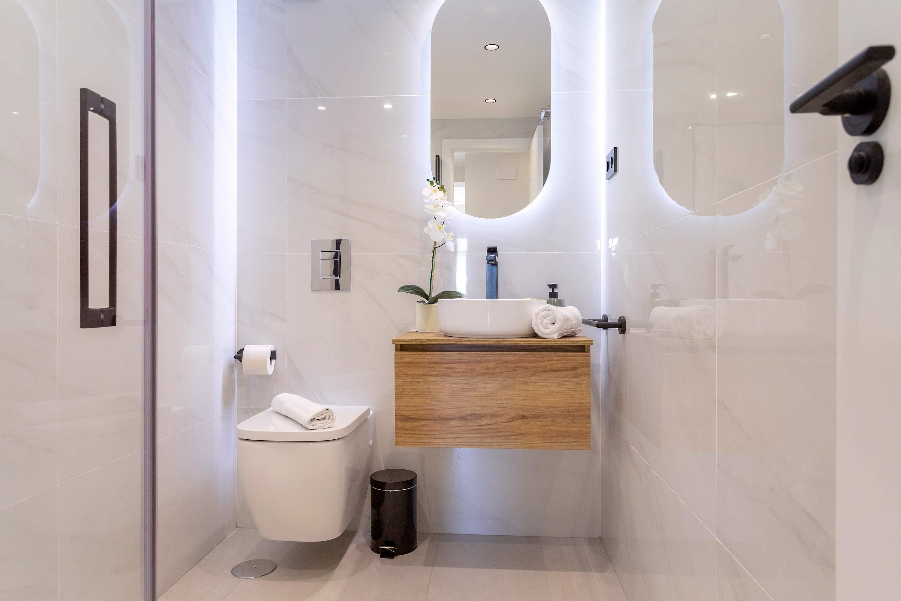 A modern bathroom with a toilet, sink, and mirror.