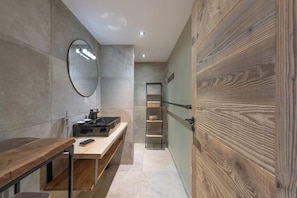 Een moderne badkamer met een houten wastafelmeubel, een spiegel en een plankunit.