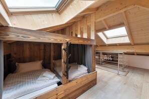 Een houten interieur met twee bedden, een dakraam en een metalen rek.
