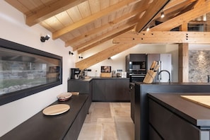 Een moderne keuken met een houten plafond, een groot raam en een stenen muur.