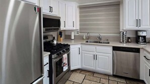 A modern kitchen with white cabinets, stainless steel appliances, and a tiled floor. - Munguia Summit Camp|Modern 2BR·Near to Snow Summit (Big Bear Lake)