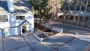 A white house with a front door, a small porch, and a fenced yard with a tree. - Munguia Summit Camp|Modern 2BR·Near to Snow Summit (Big Bear Lake)