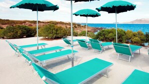 A beachside lounge area with multiple green lounge chairs and umbrellas, overlooking a coastal landscape. - Hotiday Golfo Aranci (Golfo Aranci)