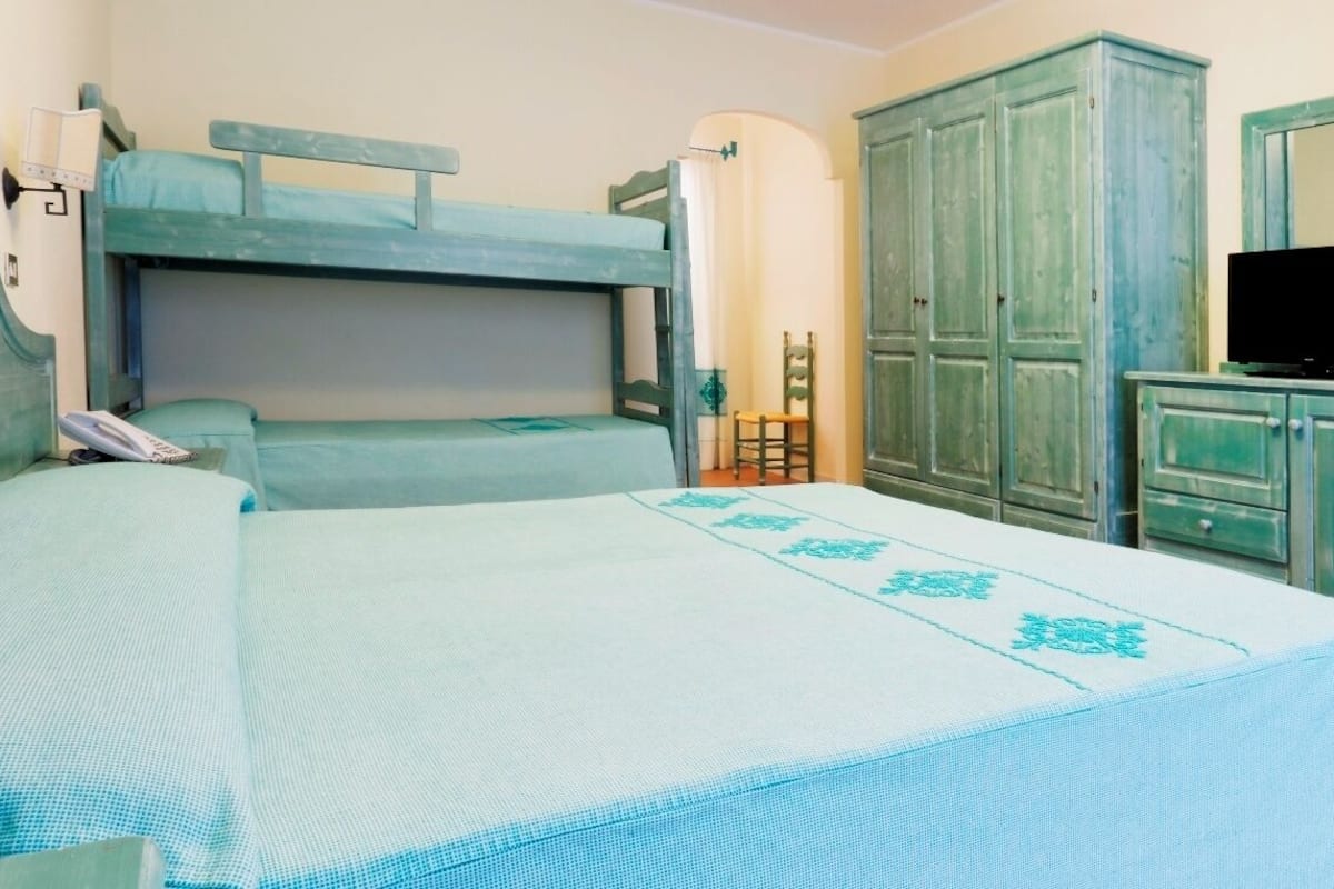 A bedroom with bunk beds, a chair, a television, and green-painted cabinets.