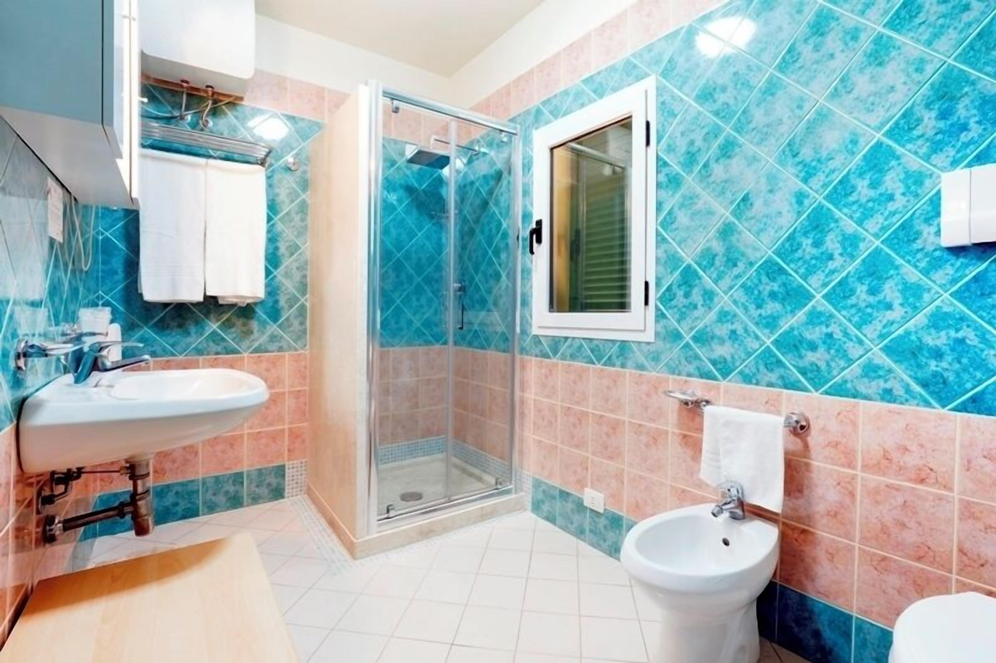 A bathroom with a glass-enclosed shower, a sink, a bidet, and a toilet.