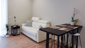 En moderne stue med en hvid sofa, et sort sofabord og en potte med en orkidé.