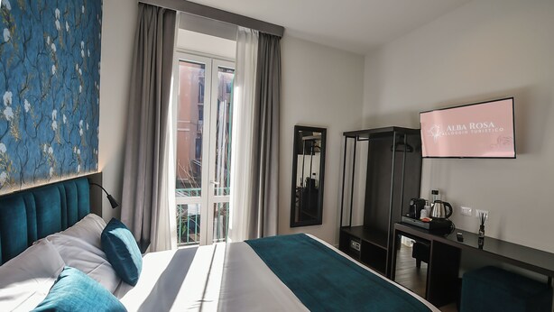Et hotelværelse med seng, skrivebord, TV og udsigt ud.