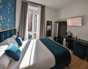 Un cuarto de hotel con cama, escritorio, televisión y vista al exterior.