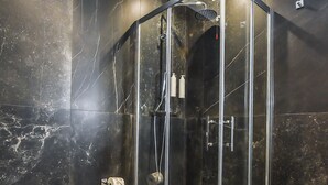 Et moderne badeværelse med en brusekabine med glaslåger, toilet og håndvask.