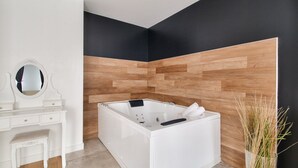 A modern bathroom with a white vanity, a large bathtub, and a wooden accent wall. - 123home- Suite & spa XL (Montevrain)