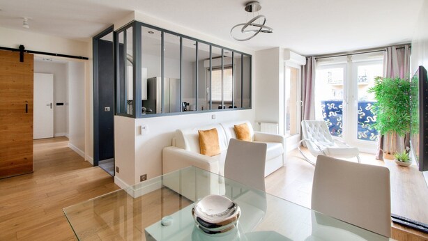 A modern living room with a glass dining table, white sofas, and a large mirror. - 123home- Suite & spa XL (Montevrain)
