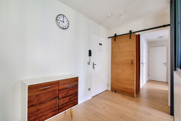Un interior moderno con un armario de madera, una puerta corredera y un reloj de pared.
