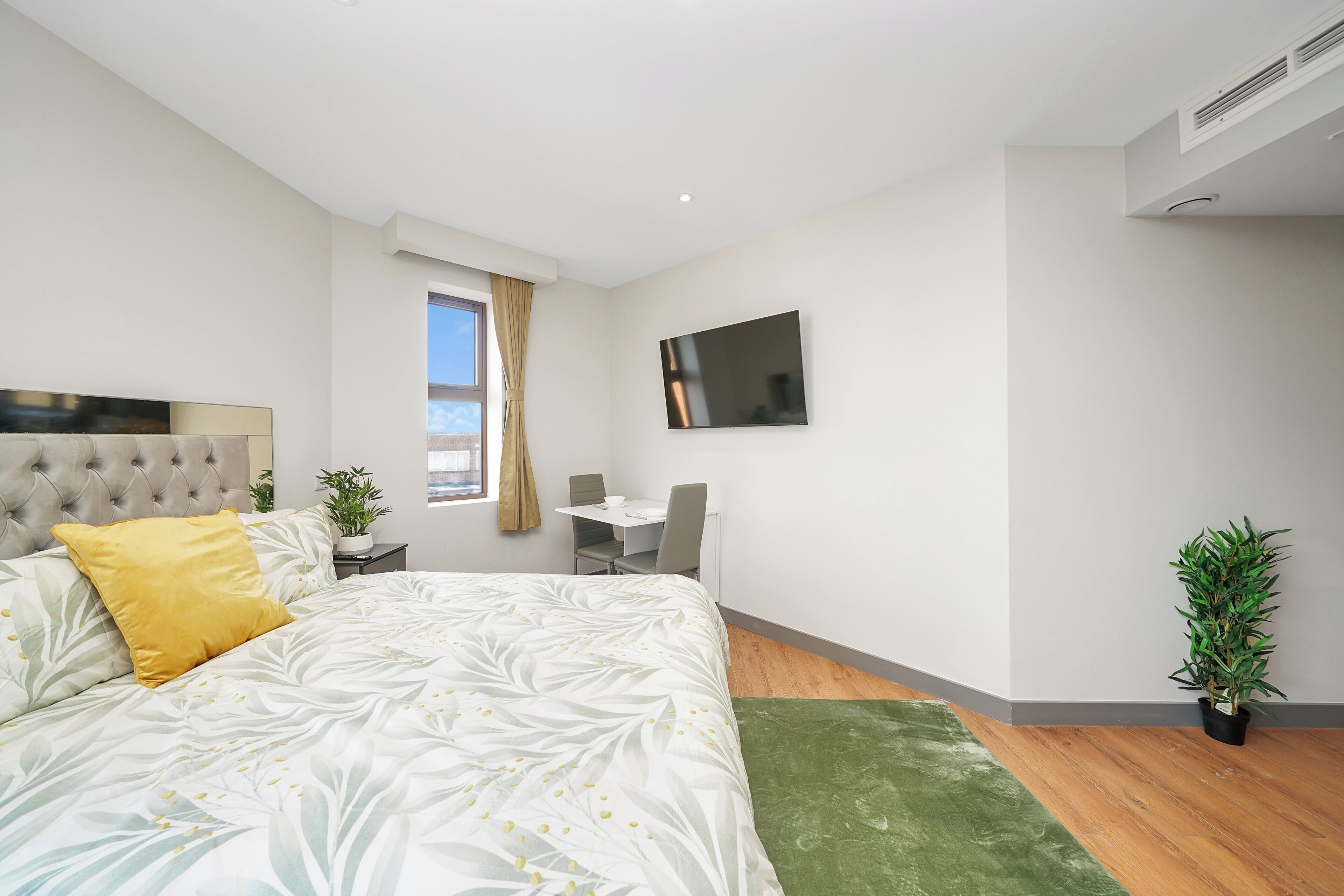 Une chambre moderne avec un grand lit, un bureau et une télévision.
