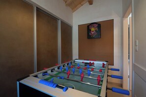 A foosball table in a room with a wooden ceiling and a framed poster on the wall.