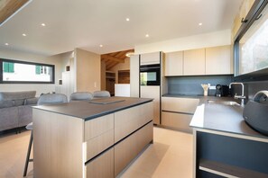 A modern kitchen with a central island, built-in appliances, and a dining area with a sofa and chairs.