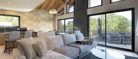 A modern living space with a sectional sofa, a dining area, and large windows.