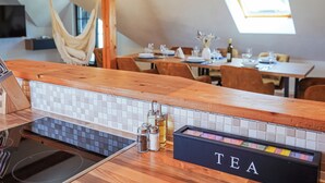 A modern kitchen with a wooden countertop, a tea station, and a dining area with a hammock.