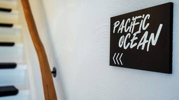 Ein schwarzes Schild mit weißer Schrift, die „PACIFIC OCEAN“ zeigt, an einer weißen Wand.