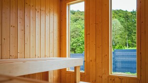 A wooden room with a large window and a wooden bench.
