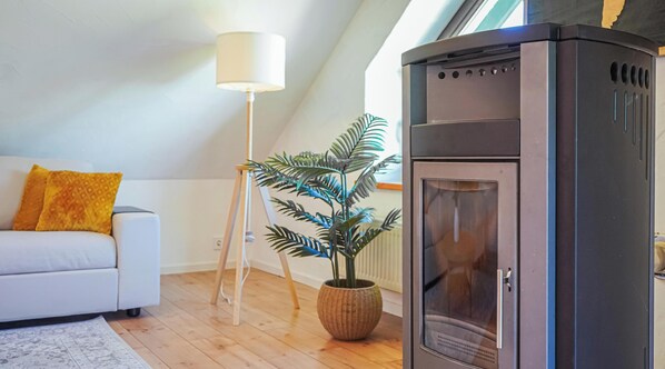 A modern living room with a white sofa, a floor lamp, a potted plant, and a built-in fireplace. - 7Seas Erholungsdomizil Bostalsee (Nohfelden)