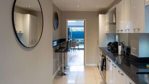 A modern kitchen with a large mirror, a clock, and a view to a dining area.