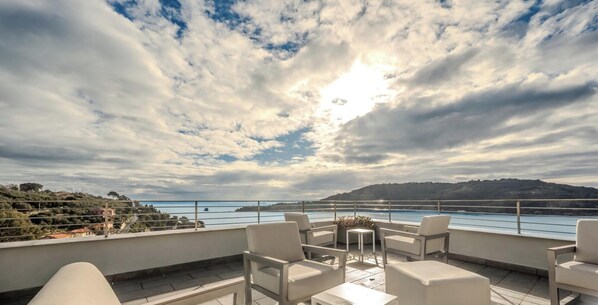 A terrace with outdoor seating and a view of a body of water and hills. - Hotiday Room Collection - Porto Venere (Portovenere)