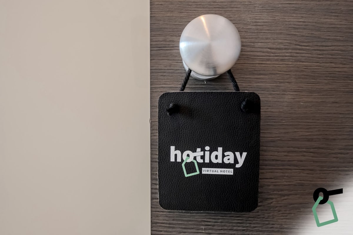A black square object with the word 'hotday' and a green square logo, hanging on a wooden surface.